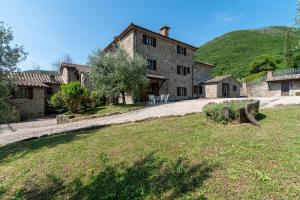 un gran edificio de piedra con una mesa y sillas en un patio en Villa Agriturismo Cuiano - Pierle, en Cortona