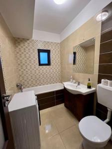 een badkamer met een toilet, een wastafel en een bad bij Red Forest Retreat 2 Rooms Flat in Chiajna