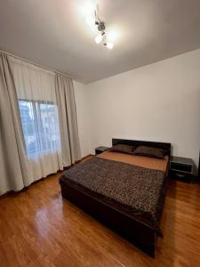 een slaapkamer met een bed en een groot raam bij Red Forest Retreat 2 Rooms Flat in Chiajna