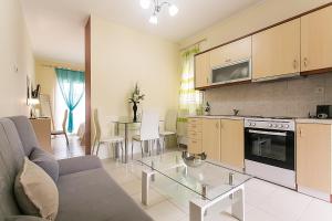 a kitchen and living room with a couch and a table at Tranquil Apartments Corfu in Kontokali