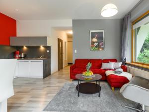 ザコパネにあるVisitZakopane - Aquapark Residence One Apartmentのリビングルーム(赤いソファ、テーブル付)