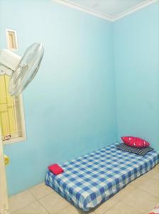 a bed in a room with a blue wall at SLAMET HOMESTAY TASIKMALAYA in Tasikmalaya