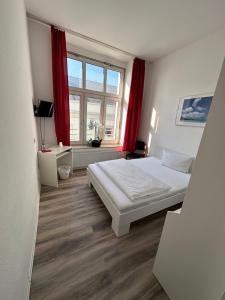 a bedroom with a bed and a window with red curtains at Hotel Astor in Wuppertal