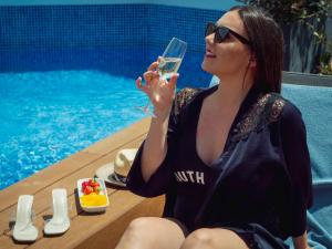 a woman holding a glass of wine by a pool at ARCELON HOTEL - From 2023 in Barcelona