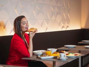 una mujer sentada en una mesa comiendo un pedazo de comida en ARCELON HOTEL - New from 2023, en Barcelona