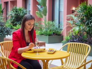 una mujer sentada en una mesa con una copa de vino en ARCELON HOTEL - 10 min walking to Sagrada Familia, en Barcelona