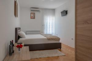 sypialnia z łóżkiem i stołem z kwiatami w obiekcie Apartments Maxi Katić w mieście Herceg Novi