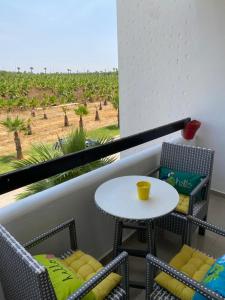 balcón con mesa, sillas y vistas a un campo en lovely and chic Appartment in asilah marina golf en Asilah