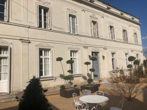 een wit gebouw met een tafel en stoelen ervoor bij Aux Marquises in Saumur