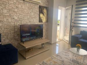 a living room with a flat screen tv on a stone wall at perfect 2 bedrooms 2 balconies pool and golf in Asilah