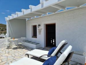 a white house with chairs and a table and a patio at Studio 1 in Patmos