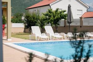 een zwembad met stoelen en een parasol en een tafel en stoelen bij Villa Porto in Mostar