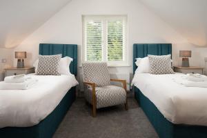 twee bedden in een kamer met een stoel en een raam bij Sunset View, Hot Tub Haven for max 8 people in Chatton