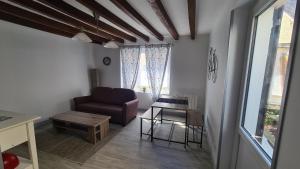 ein Wohnzimmer mit einem Sofa und einem Tisch in der Unterkunft Petite maison cosy wifi avec terrasse in Montigny-le-Gannelon