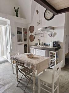cocina con mesa, sillas y reloj en Leccino Suite, en Matino