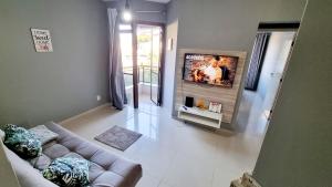 sala de estar con sofá y TV de pantalla plana en Apart Hotel Guarapuvu, en Florianópolis