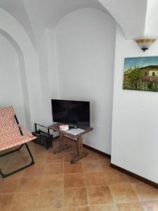 uma sala de estar com uma mesa e uma televisão em Casa Monique em Badalucco