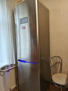 einen Kühlschrank aus Edelstahl in einer Küche mit einem Stuhl in der Unterkunft Трьохкімнатна квартира неподалік центру in Ternopil