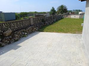 a stone patio with a fence and a yard at Casa San Miguel 93 santander in Santander