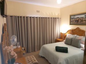 a bedroom with a bed and a window with curtains at Mitat Guesthouse in Beaufort West