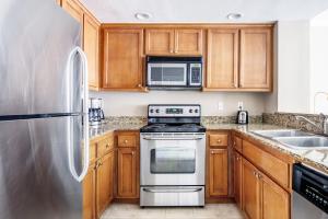eine Küche mit Holzschränken und Edelstahlgeräten in der Unterkunft Santa Clara 1BR w Parking Pool nr Dining SFO-411 in Santa Clara
