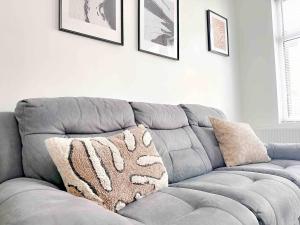 a gray couch with a pillow on it in a living room at Central City Townhouse Leicester - 3 Bedroom House in Leicester