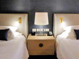 a bedroom with two beds and a lamp on a night stand at Fairmont Rio de Janeiro Copacabana in Rio de Janeiro