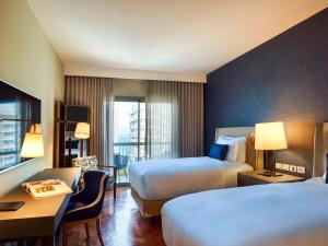a hotel room with two beds and a desk at Fairmont Rio de Janeiro Copacabana in Rio de Janeiro