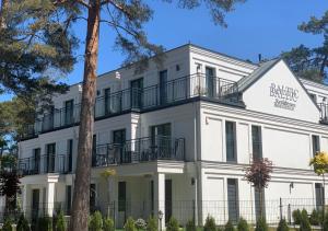 biały budynek z balkonem na górze w obiekcie Baltic Residence Apartamenty Alkam apartament nr 7, 8 - Klimatyzowany, Warszawska 11 w Pobierowie