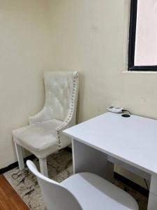 une chaise blanche assise à côté d'un bureau blanc et d'une chaise blanche dans l'établissement Forest's Simplistic Home with a dedicated study, à Nairobi