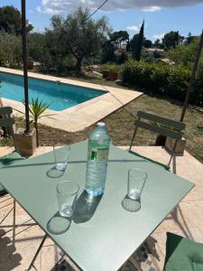 Una botella de agua sentada en una mesa con vasos. en Hauteurs de Toulon : Charmant studio piscine en Toulon