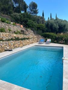 una piscina con 2 sillas y una pared de piedra en Hauteurs de Toulon : Charmant studio piscine en Toulon