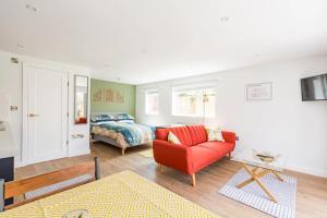 a living room with a red couch and a bed at Charming Chester Studio with private garden & free parking in Chester