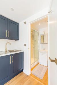 uma cozinha com armários azuis e um lavatório em Charming Chester Studio with private garden & free parking em Chester