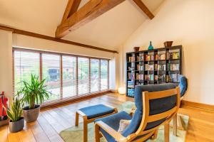 a living room with two chairs and a book shelf at Owl Barn in Sculthorpe