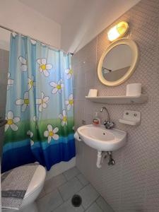 ein Badezimmer mit einem Waschbecken und einem Duschvorhang mit Blumen in der Unterkunft Project Town in Chora, Ios