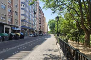 a city street with buildings and a fence and trees at Apartamento Turquesa in Zaragoza
