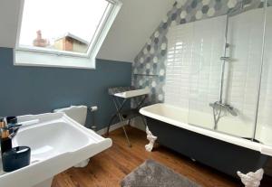 een badkamer met een bad, een wastafel en een raam bij La Côte in Granville