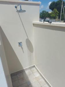 a white wall with a shower with a tile floor at tata Uccio in Matino