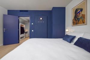 a bedroom with a large white bed with blue walls at C-Hotels Burlington in Ostend