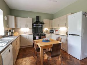 a kitchen with a wooden table and a white refrigerator at Brewery House in Newton Stewart