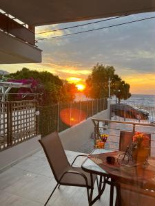 un balcón con una mesa y una silla y la puesta de sol en Akrotiri Luxury Suites en Trápeza