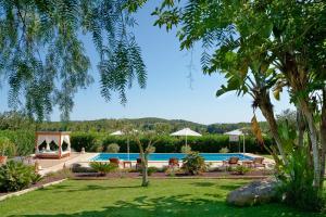 una piscina in un cortile con sedie e alberi di Villa Mago a Santa Gertrudis de Fruitera