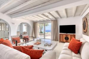 a living room with white furniture and a tv at Villa Ainar in Tinos