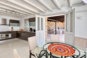 a kitchen and dining room with a glass table and chairs at Villa Ainar in Tinos