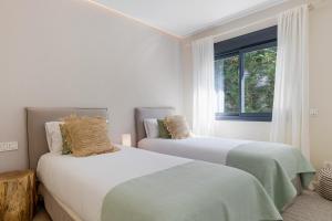 two beds in a white room with a window at Casa Las Palmeras in Marbella