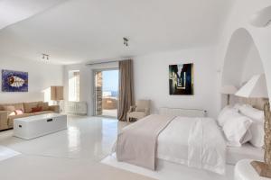 a white bedroom with a bed and a living room at Villa Ainar in Tinos Town