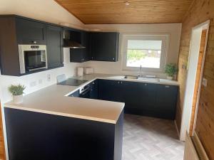 a kitchen with black cabinets and a sink and a window at Hideaway Lodge in Carnforth