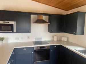 a kitchen with black cabinets and a counter top at Hideaway Lodge in Carnforth