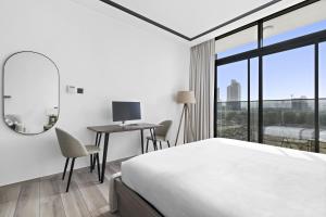 Schlafzimmer mit einem Bett und einem Schreibtisch mit einem Spiegel in der Unterkunft A Living Luxury Studio Nicholas Residence JVC in Dubai